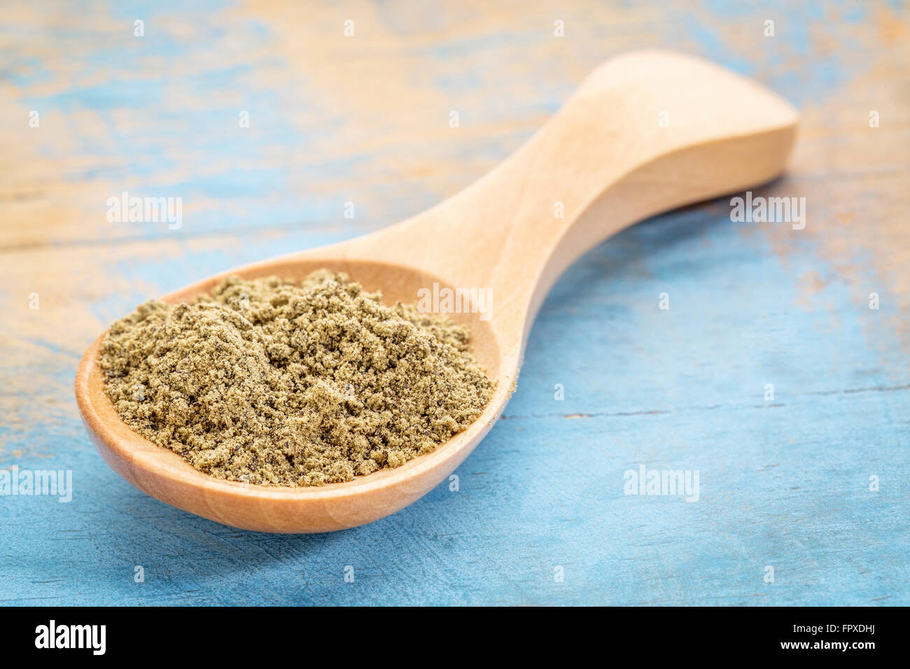 I semi di canapa proteine in polvere su un cucchiaio di legno contro blu dipinta legno grunge Foto Stock