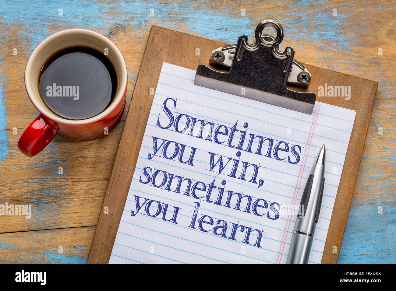 A volte si vince e a volte si impara - testo motivazionale su una clipboard con una tazza di caffè Foto Stock