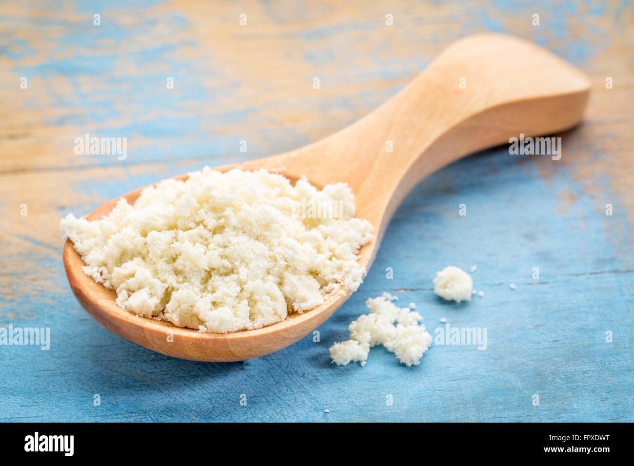 La proteina del siero di latte in polvere in un cucchiaio di legno contro blu dipinta legno grunge Foto Stock