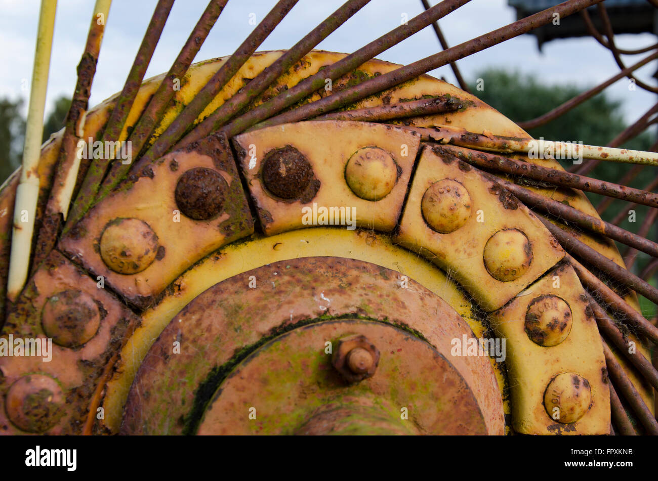 Arrugginimento giallo farm machinery seduti in un paddock Foto Stock