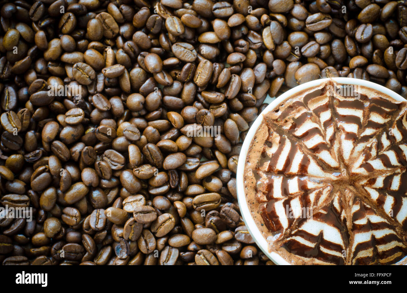 Una tazza di latte art sul chicco di caffè sfondo Foto Stock