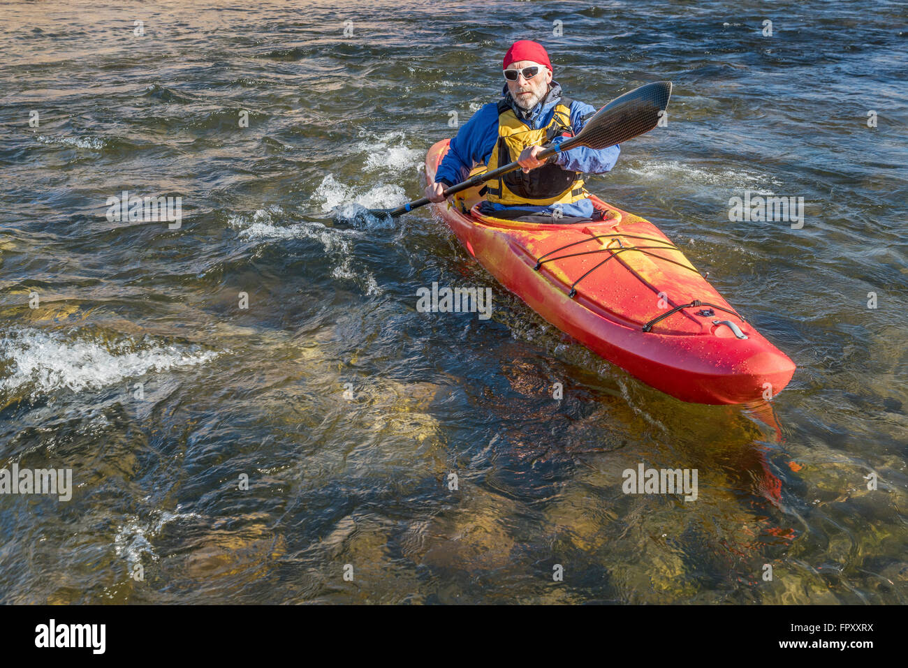 Senior maschile è paddler paddling whitewater kayak su un fiume turbolento Foto Stock