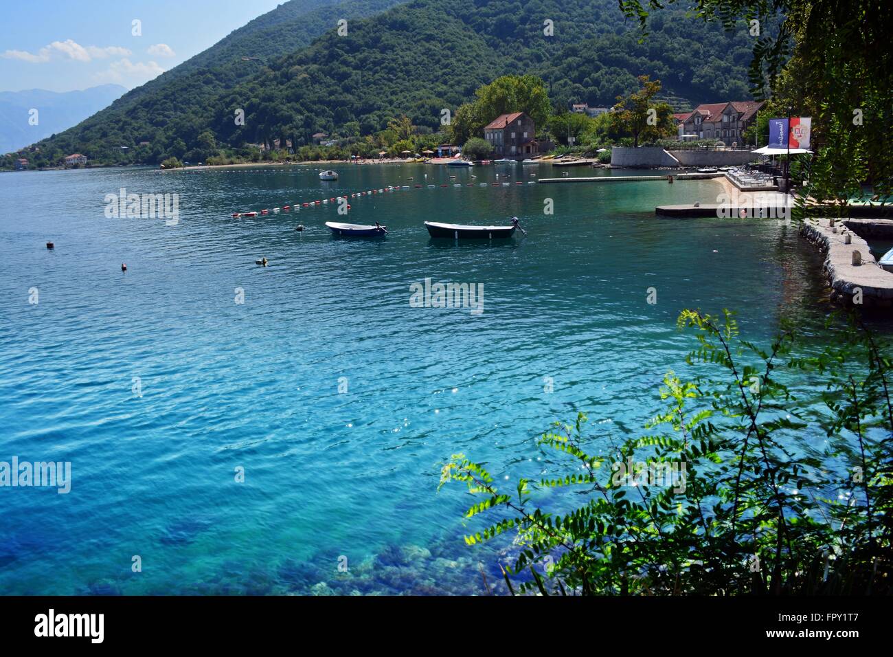 Le montagne incontrano il mare; idilliaca baia con acque chiare e di una spiaggia tranquilla nel villaggio di Morinje, la Baia di Kotor, Montenegro Foto Stock
