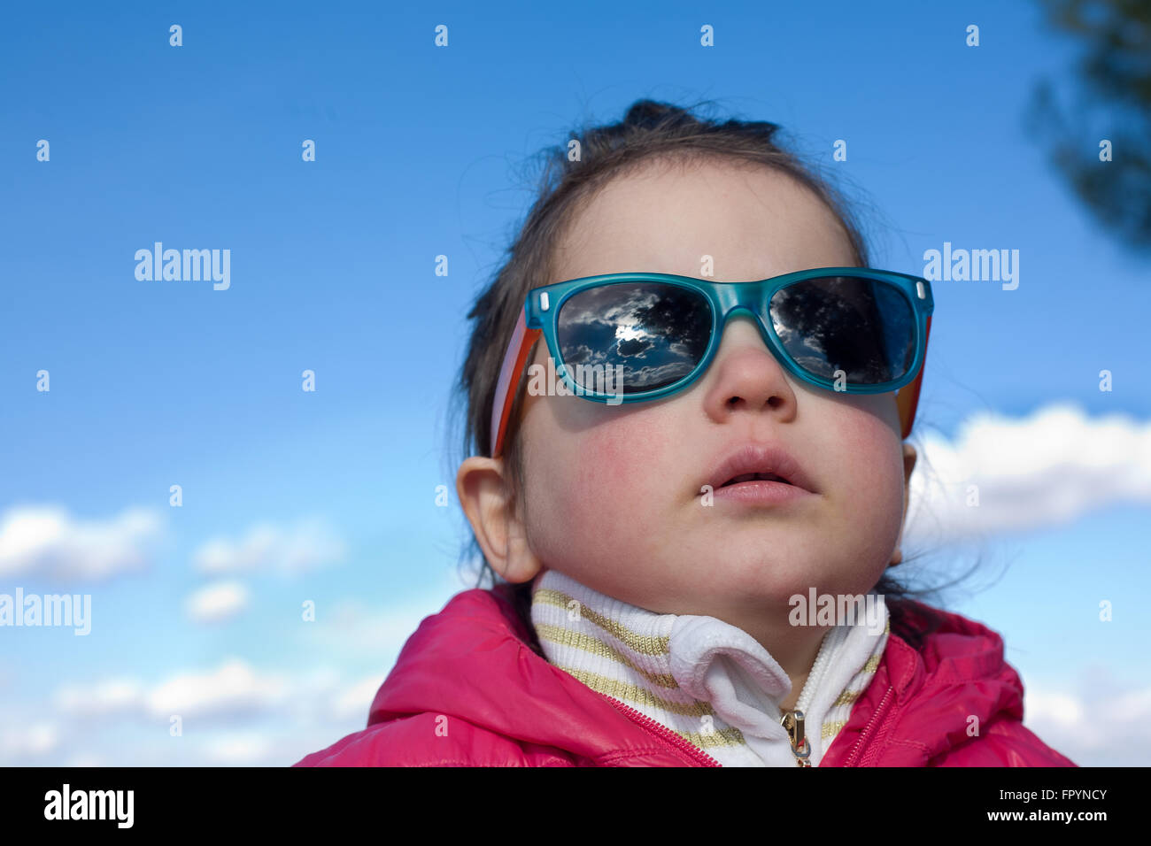 Ritratto di carino 2,5 anni toddler ragazza con bambini moda occhiali da sole con la casacca oltre il cielo blu con nuvole di sfondo Foto Stock