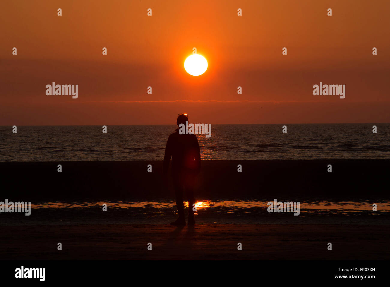 Formby, Merseysude, UK. 20 Mar, 2016. Un uomo a camminare sulla spiaggia si stagliano contro il sole di setting, come il primo giorno di primavera giunge ad una estremità su Formby beach, Formby, Merseyside, il 20 marzo 2016. Credito: Harry Whitehead/Alamy Live News Foto Stock