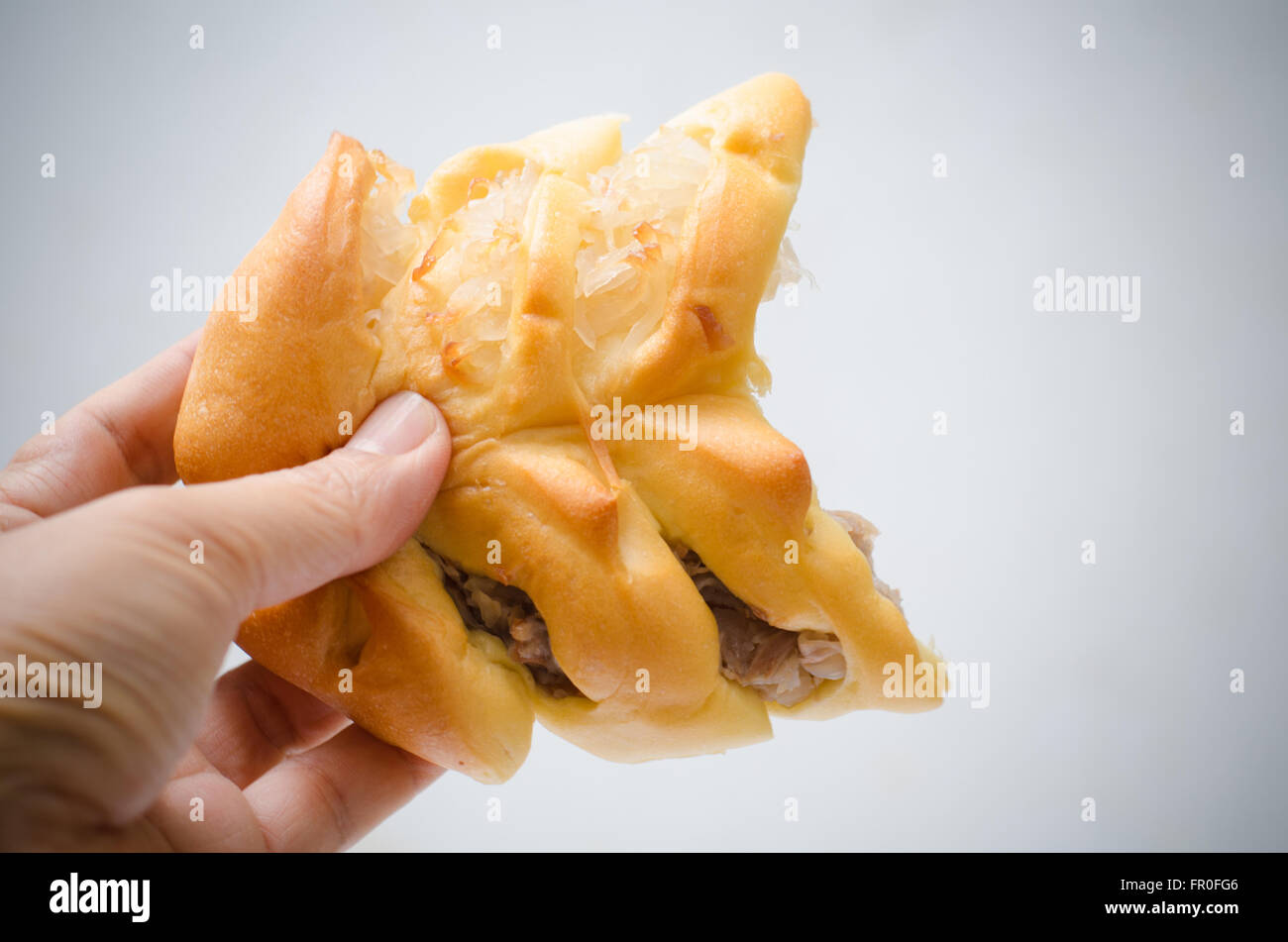 Il pane è strappato a metà in mano maschio su sfondo bianco Foto Stock