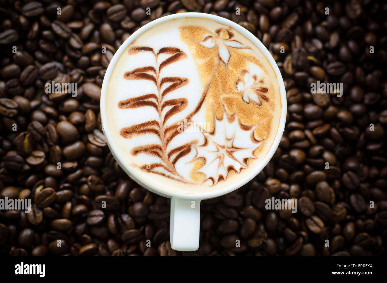 Una tazza di latte art sul chicco di caffè sfondo Foto Stock
