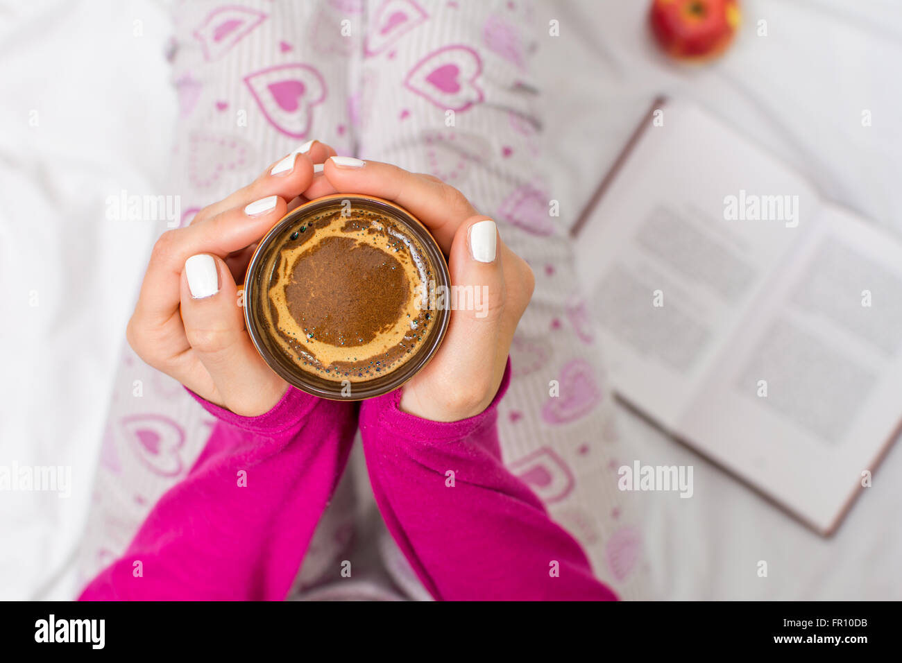 Donna con una tazza di caffè al mattino nel letto Foto Stock