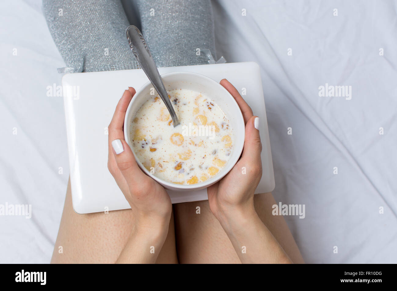 Ragazza di mangiare i cereali per la colazione a letto Foto Stock