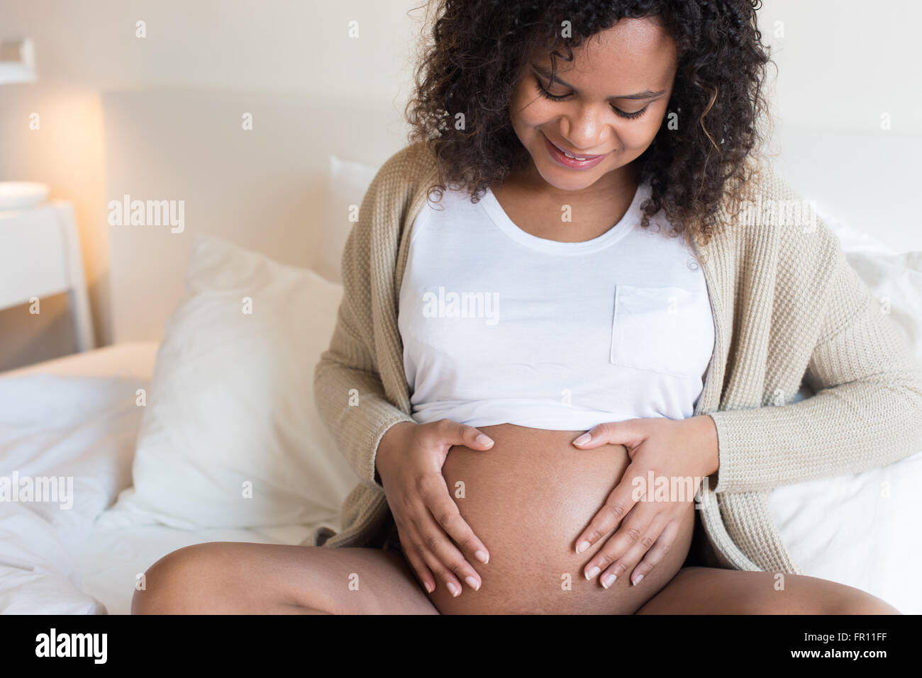 Felice afro donna mostrando il suo ventre in gravidanza Foto Stock