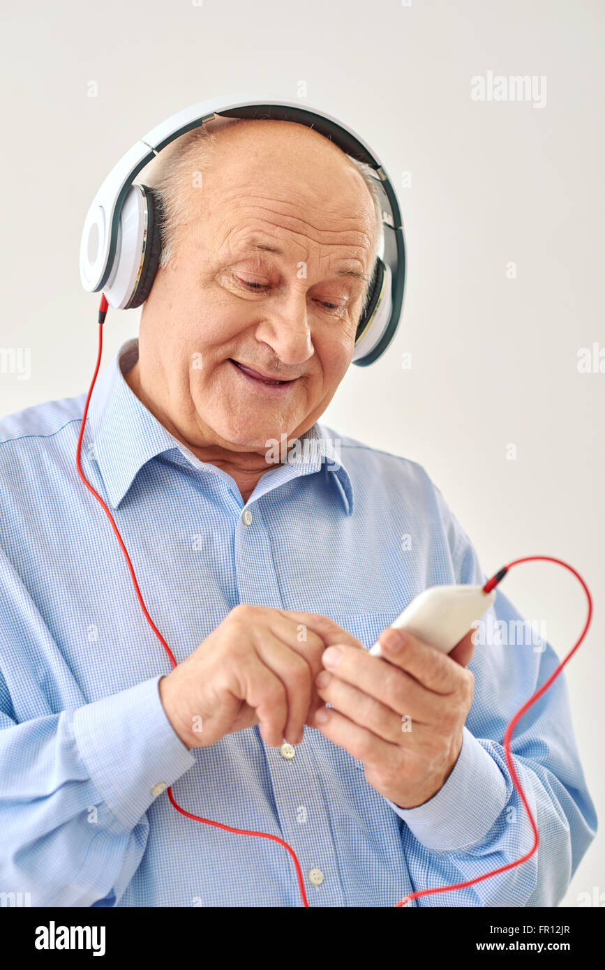 Il vecchio uomo che ascolta la musica sulle cuffie Foto Stock
