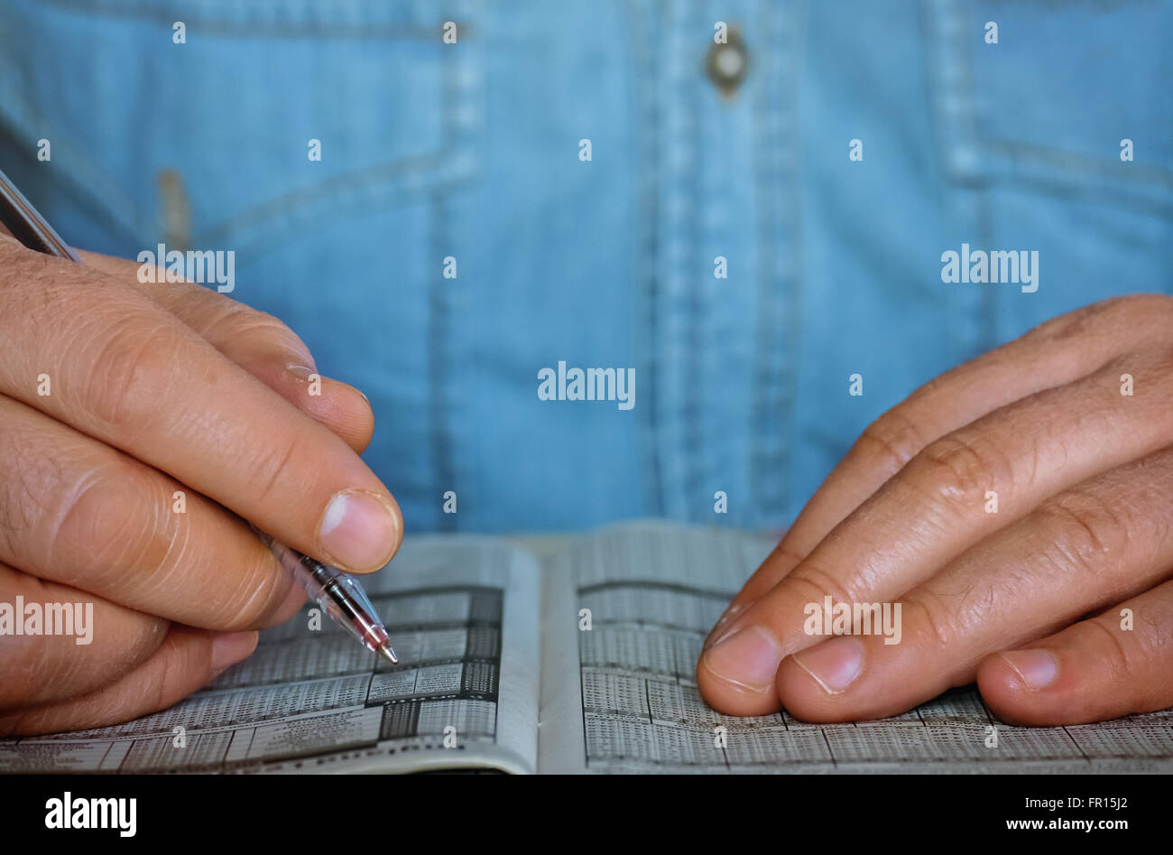 Primo piano di due mani maschili in possesso di una penna sulla carta stampata Foto Stock