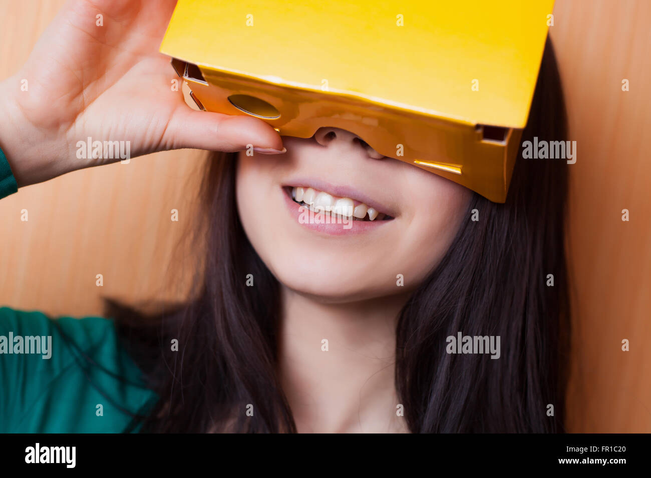 Sorridente ragazza giovane la riproduzione di uno smart phone gioco con il suo augmented o della realtà virtuale auricolare Foto Stock
