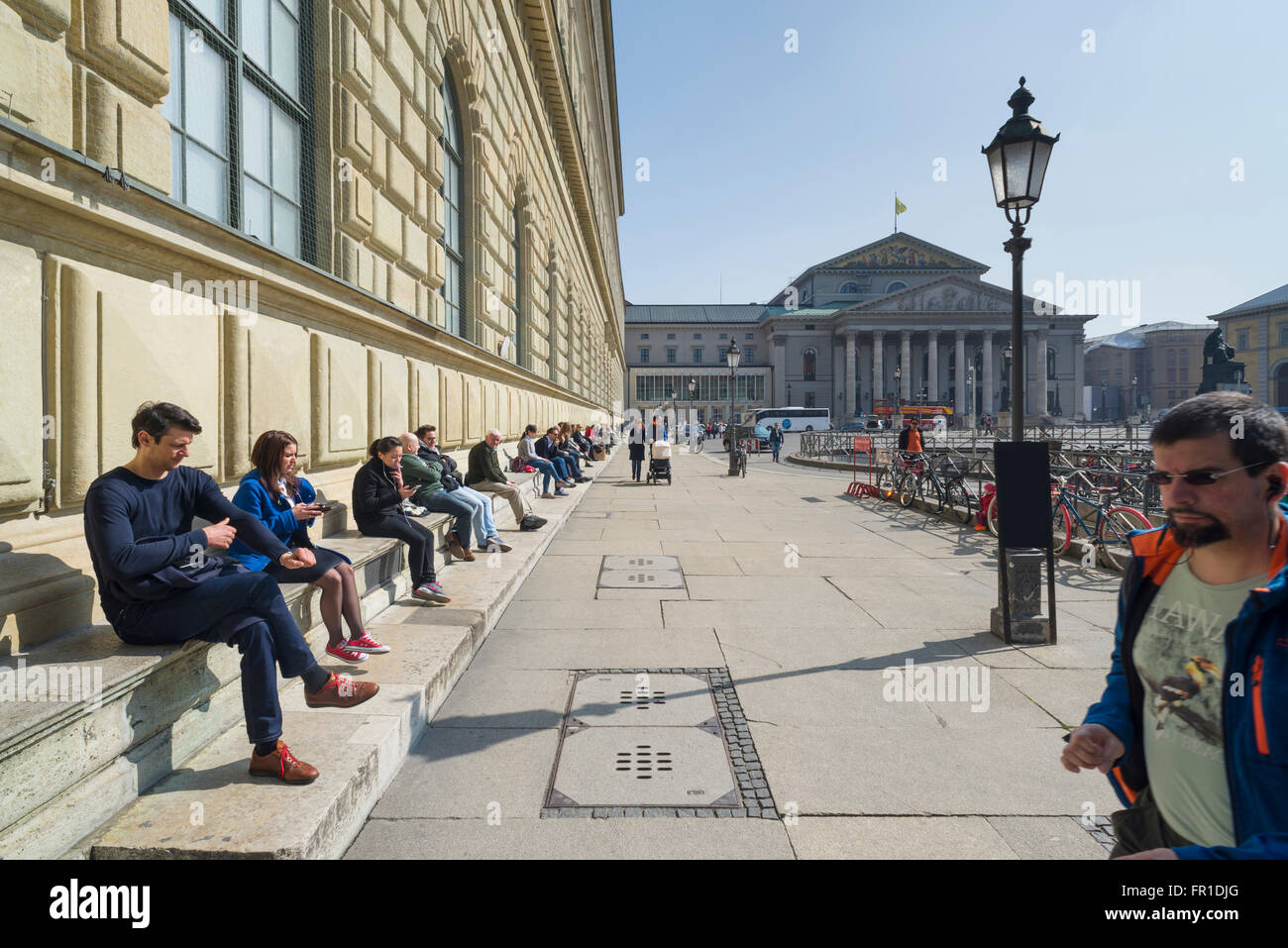La gente seduta al royal Königsbau palace e il teatro di Monaco di Baviera godersi il caldo sole di primavera,Baviera,Germania Foto Stock