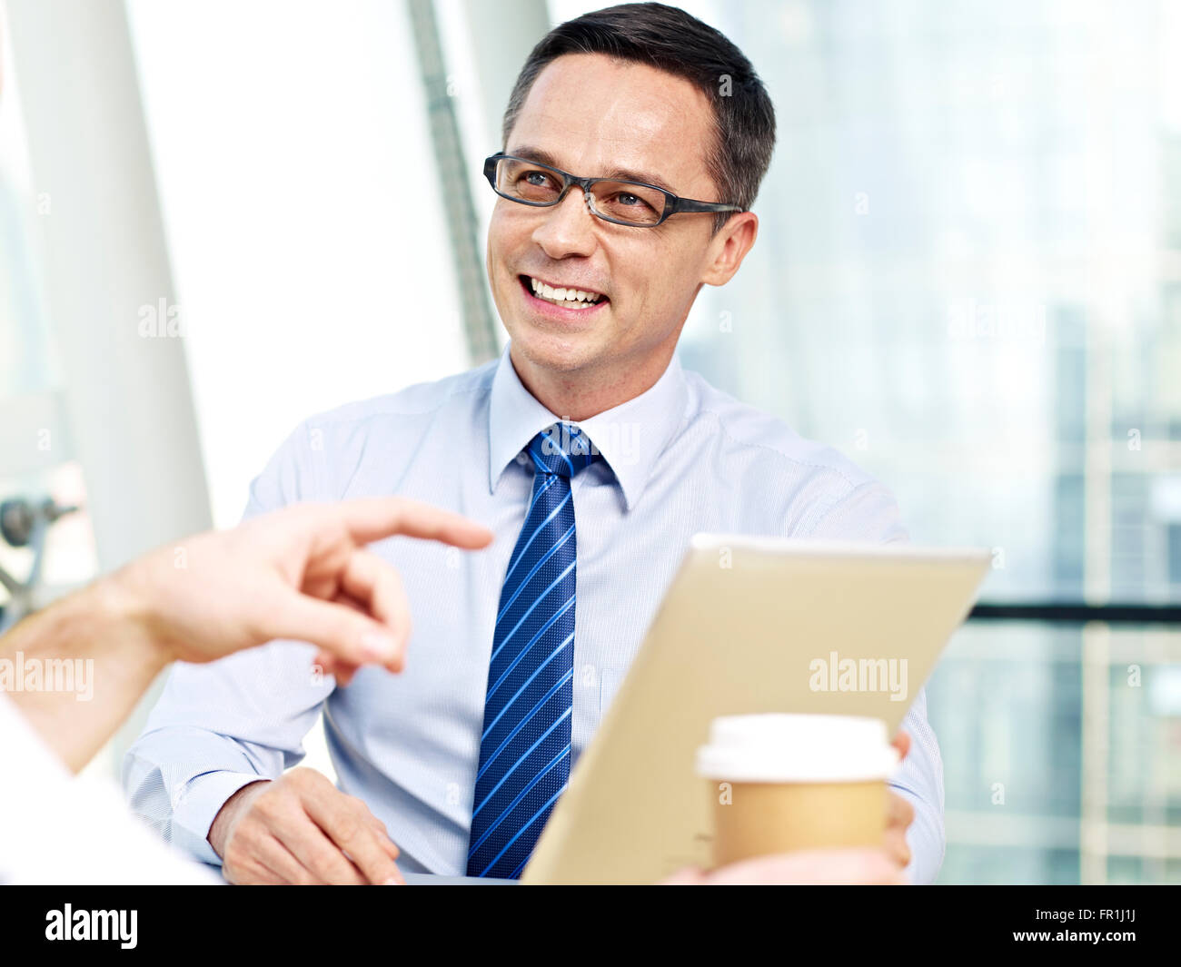 Business man holding computer tablet ascolto di qualcuno e sorridente Foto Stock