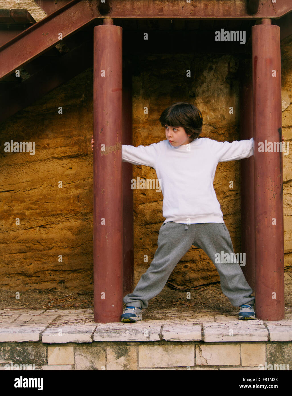 Giovane età elementare ragazzo giocando all'aperto ion un parco giochi Foto Stock