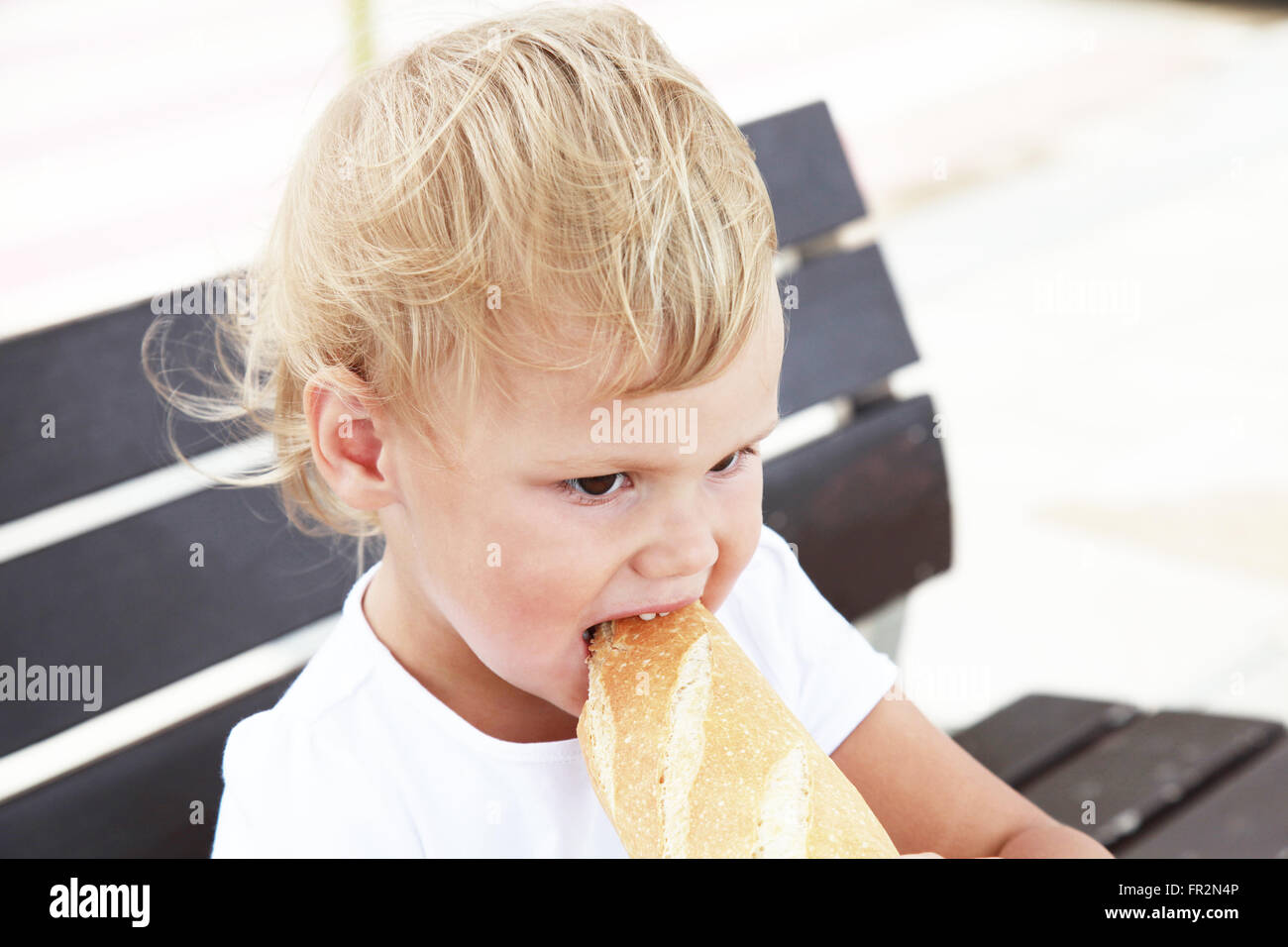 Outdoor close up ritratto di carino bionda caucasica bambina mangiare grandi baguette francese Foto Stock