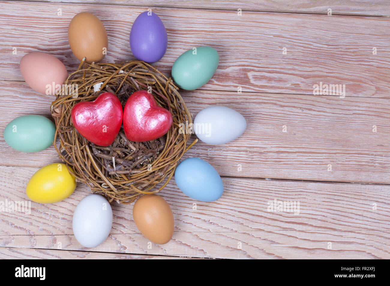 Mazzetto di Pasqua uova colorate nel nido di uccelli su sfondo di legno Foto Stock