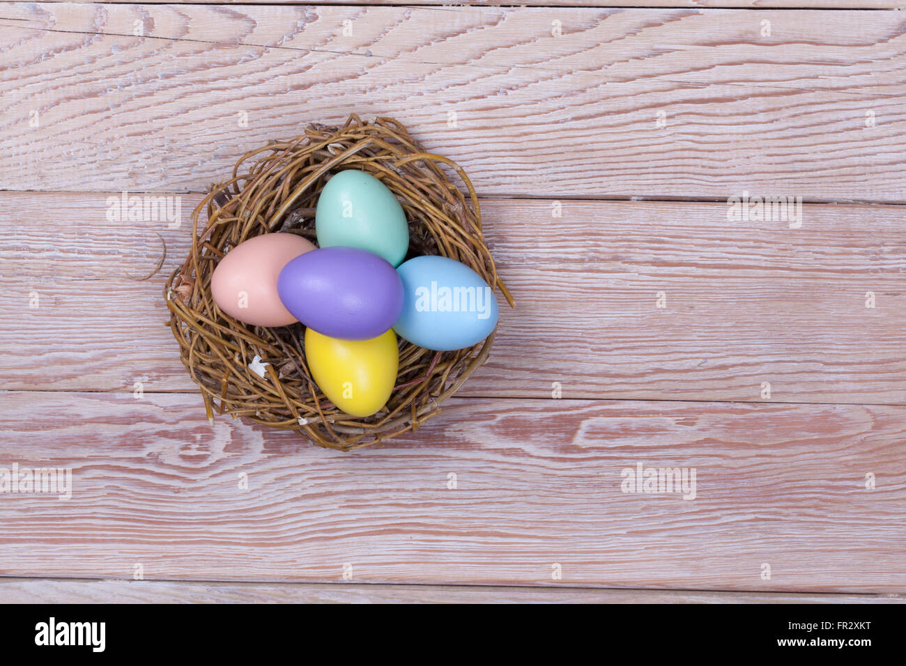 Mazzetto di Pasqua uova colorate nel nido di uccelli su sfondo di legno Foto Stock