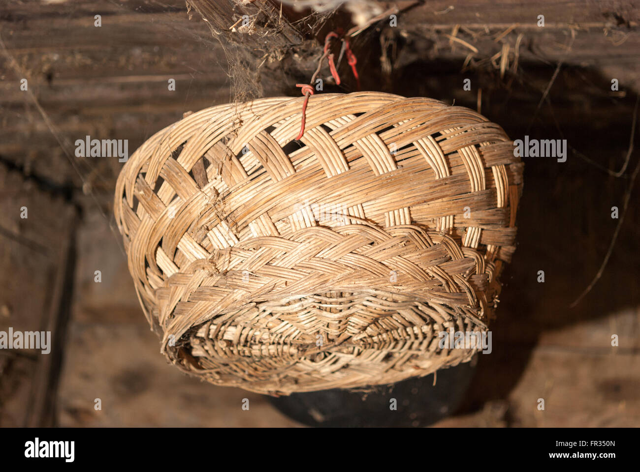 Cesto in Vimini appeso sotto il soffitto in un vecchio fienile closeup. Foto Stock