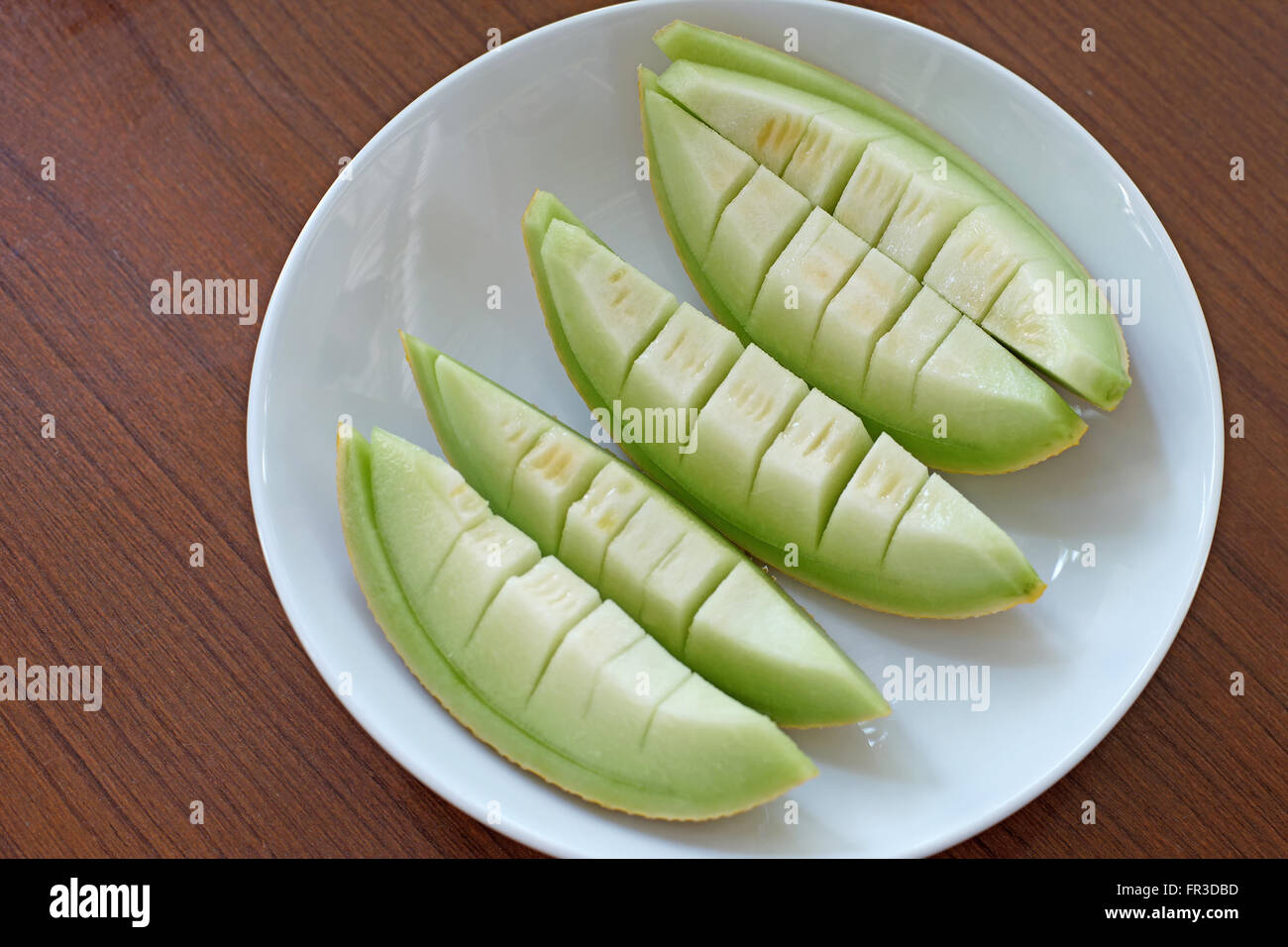 Sbucciare il melone Cantalupo in piastra bianca sul tavolo di legno Foto Stock