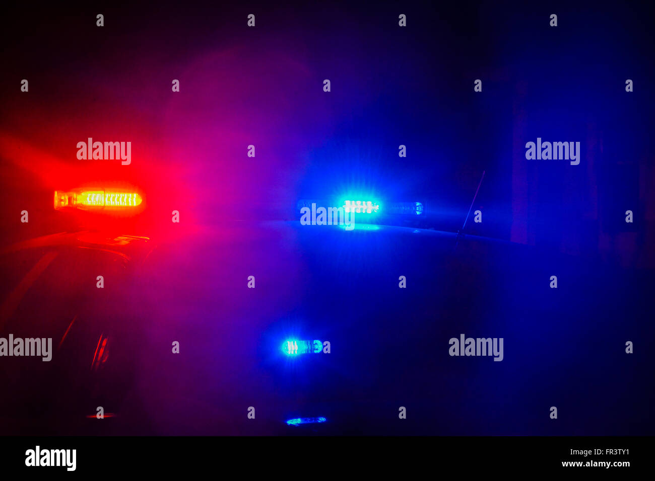 Luci rosse e blu lampeggianti per auto della polizia in cima a un'auto di pattuglia risplendono nel nero della notte mentre svolgevano attività di polizia Foto Stock