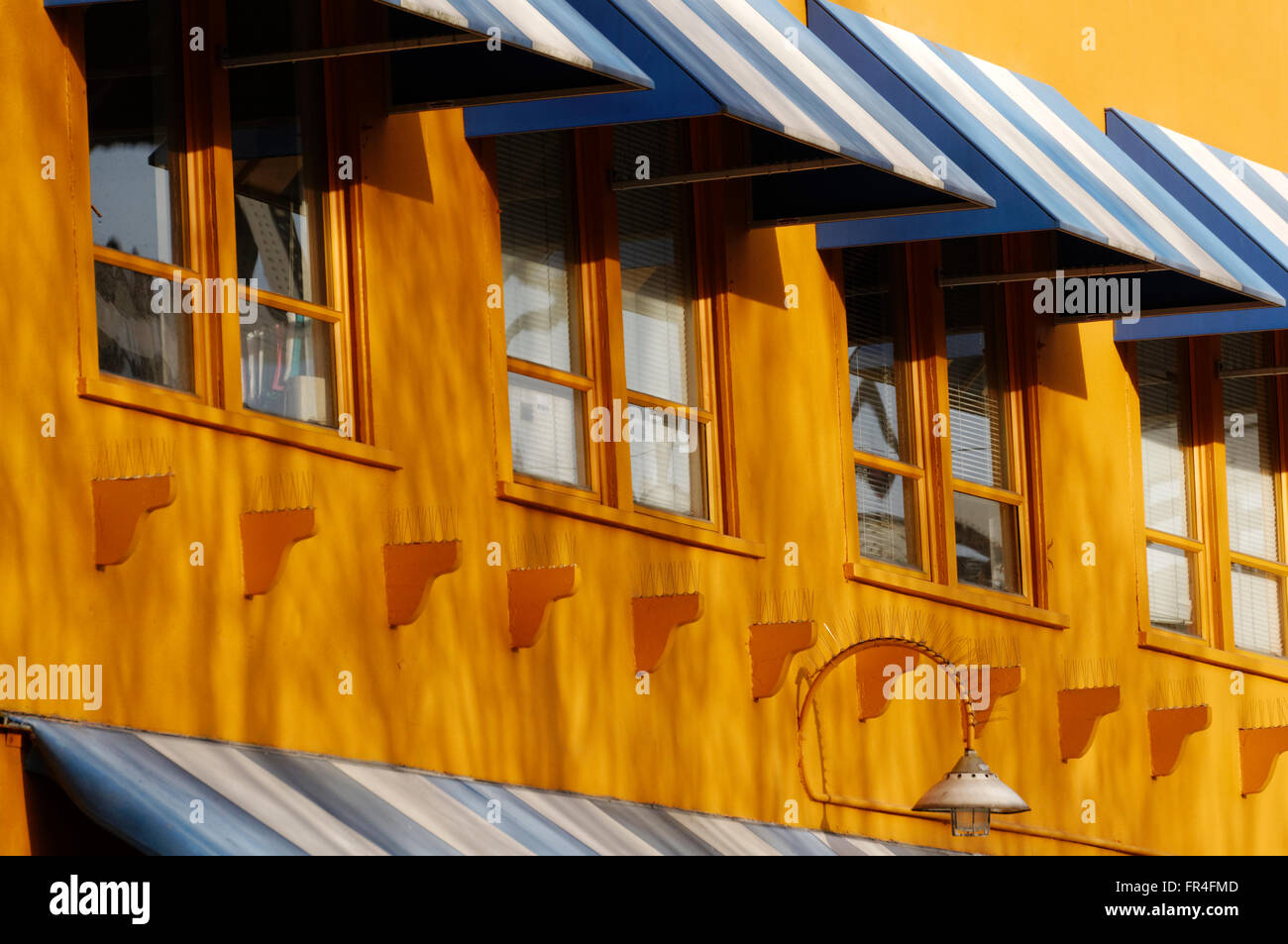 Blu e bianco tende finestra sulla facciata di una parete giallo su Granville Island, Vancouver, British Columbia, Canada Foto Stock