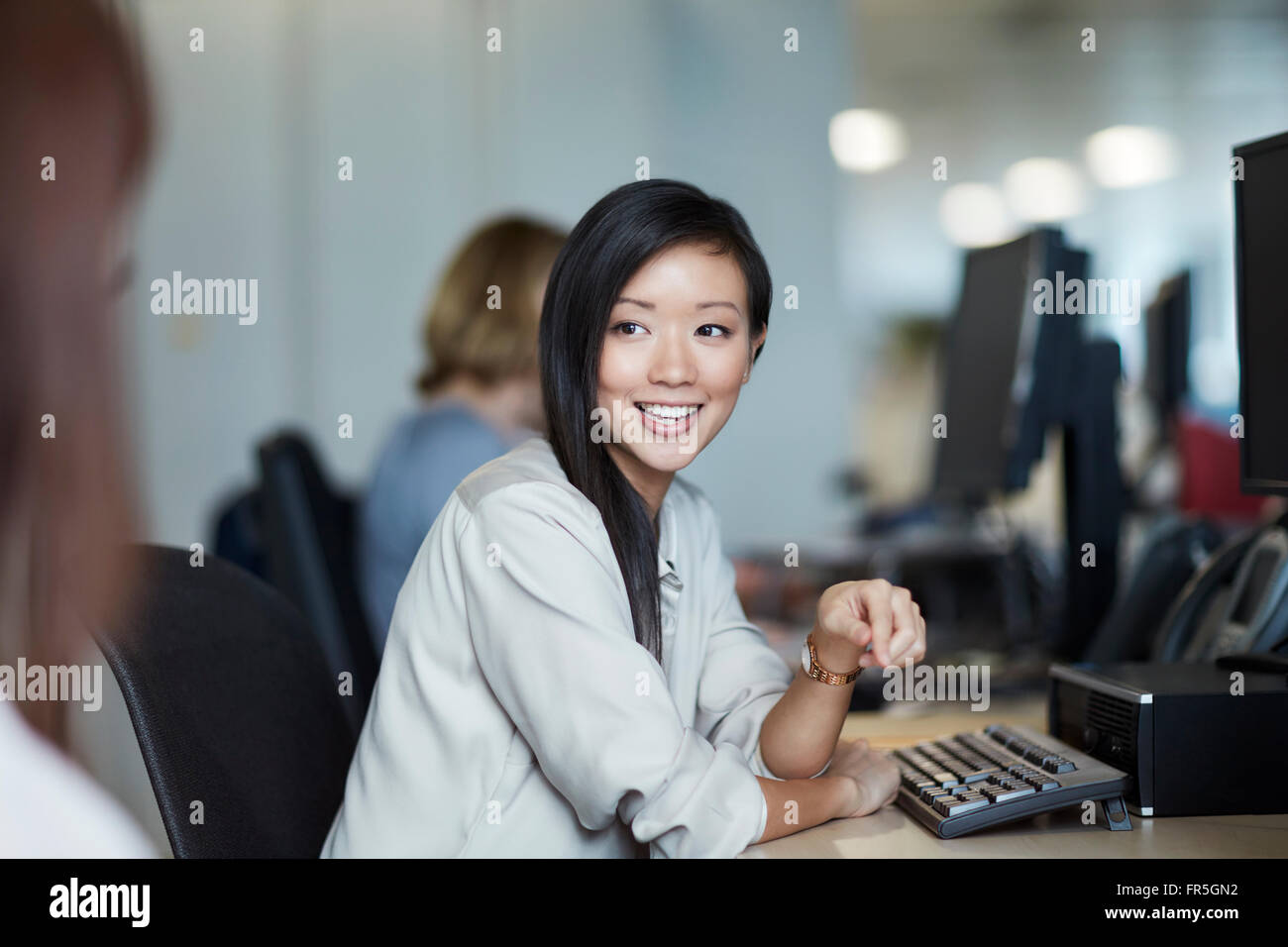 Sorridente imprenditrice parlando a un collega in ufficio Foto Stock