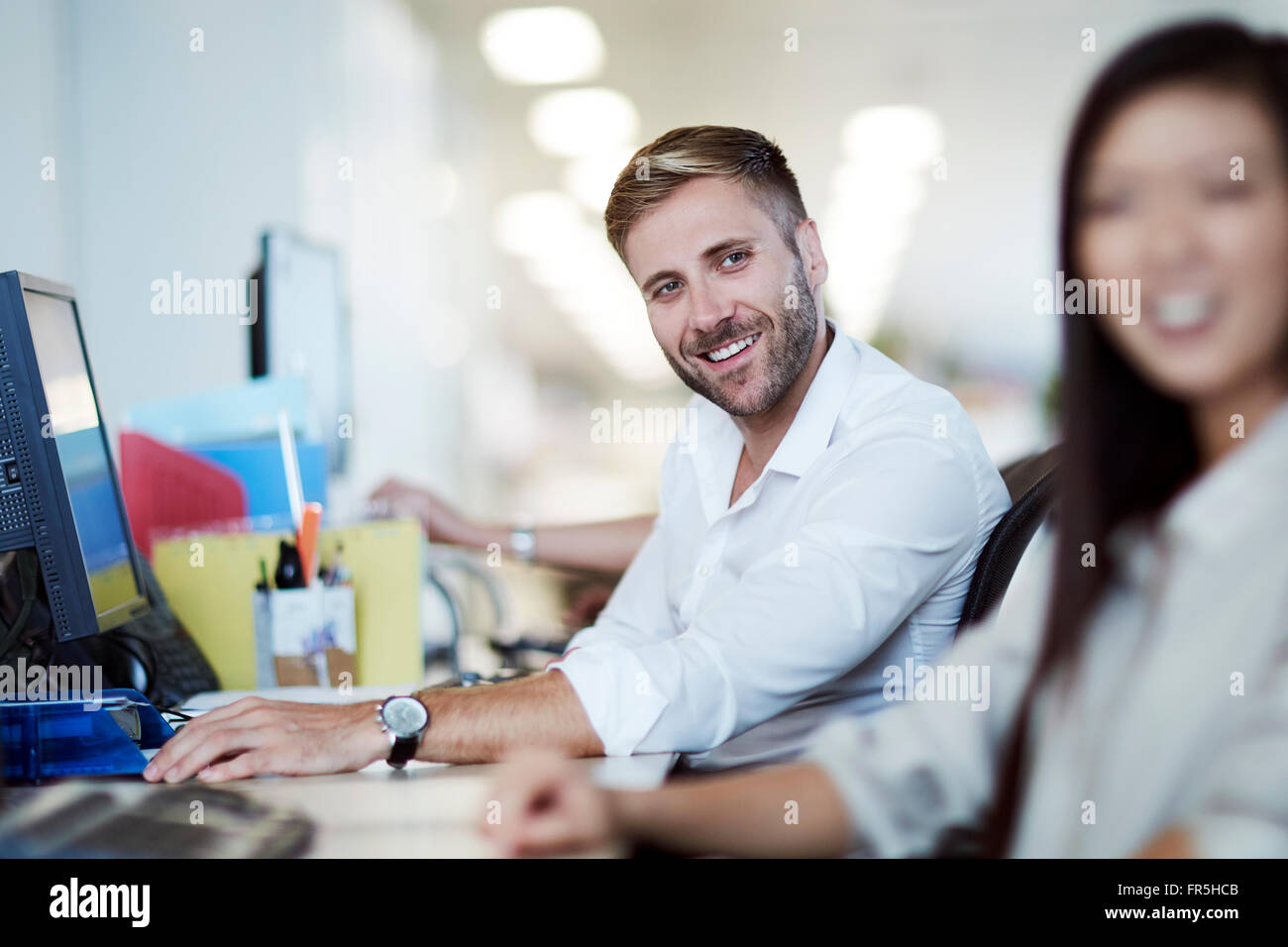 Imprenditore sorridente al computer in ufficio Foto Stock