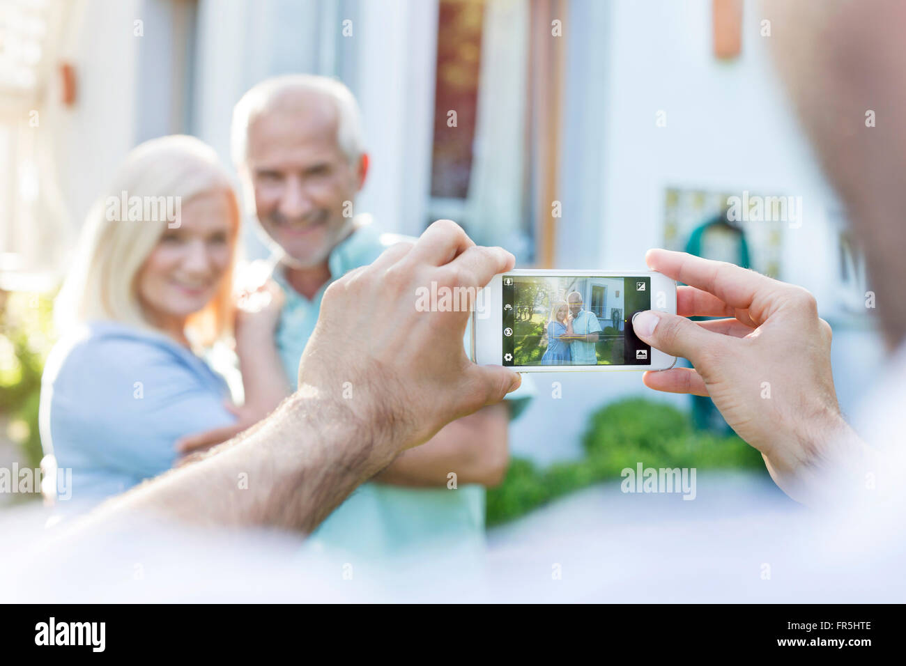 L'uomo fotografare la coppia senior con la fotocamera del telefono Foto Stock