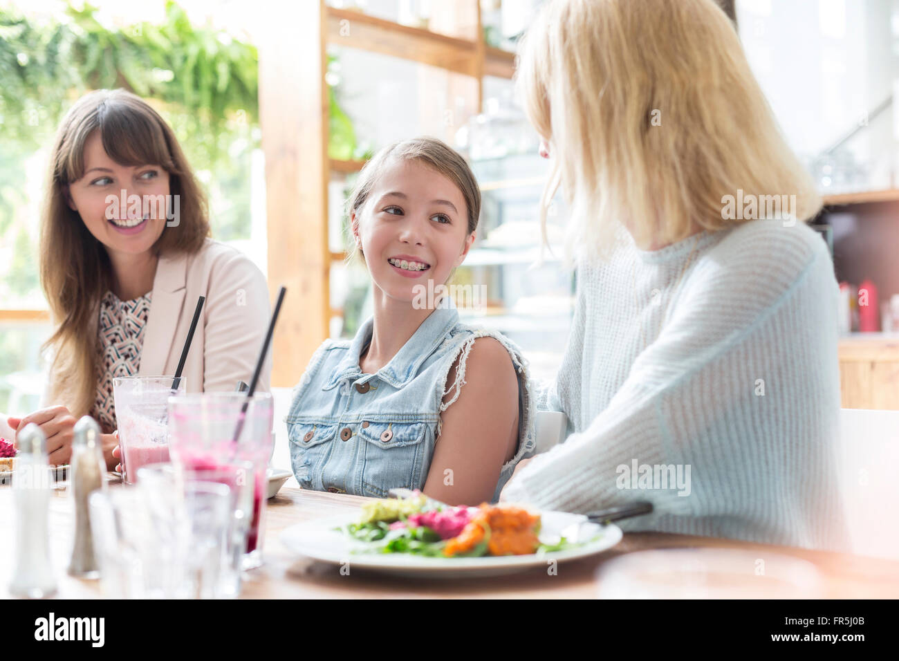 Le donne e la ragazza di mangiare pranzo al cafè tabella Foto Stock