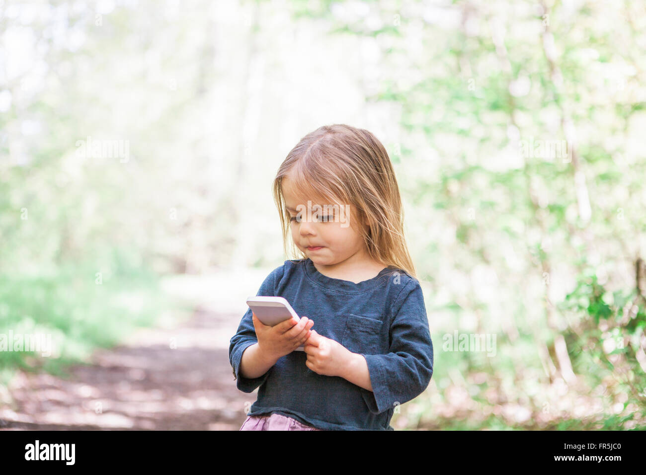 Il Toddler ragazza utilizzando il telefono cellulare in posizione di parcheggio Foto Stock