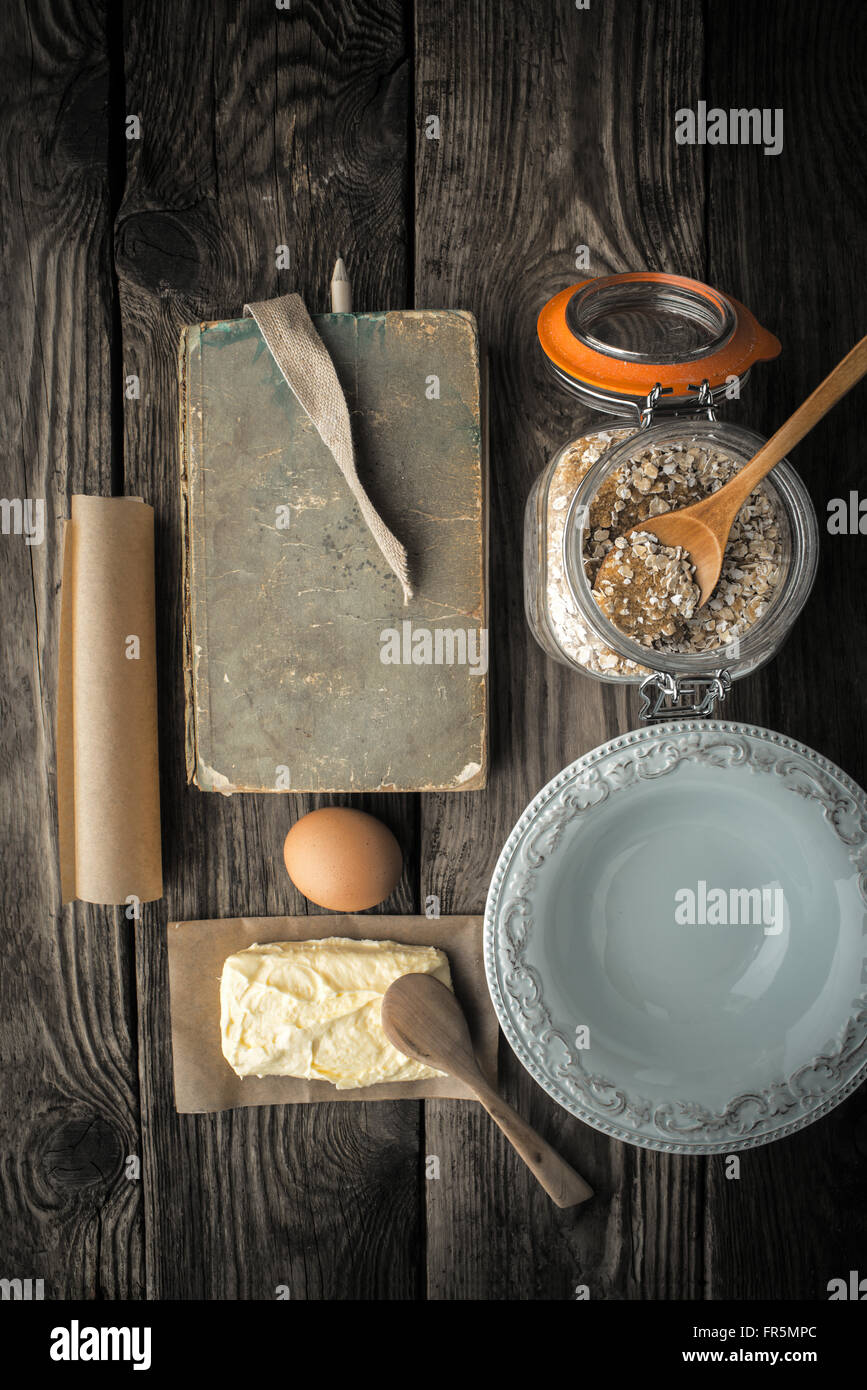 Libro di ricette, piastra e gli ingredienti per i biscotti su una tavola di legno super verticale still life Foto Stock