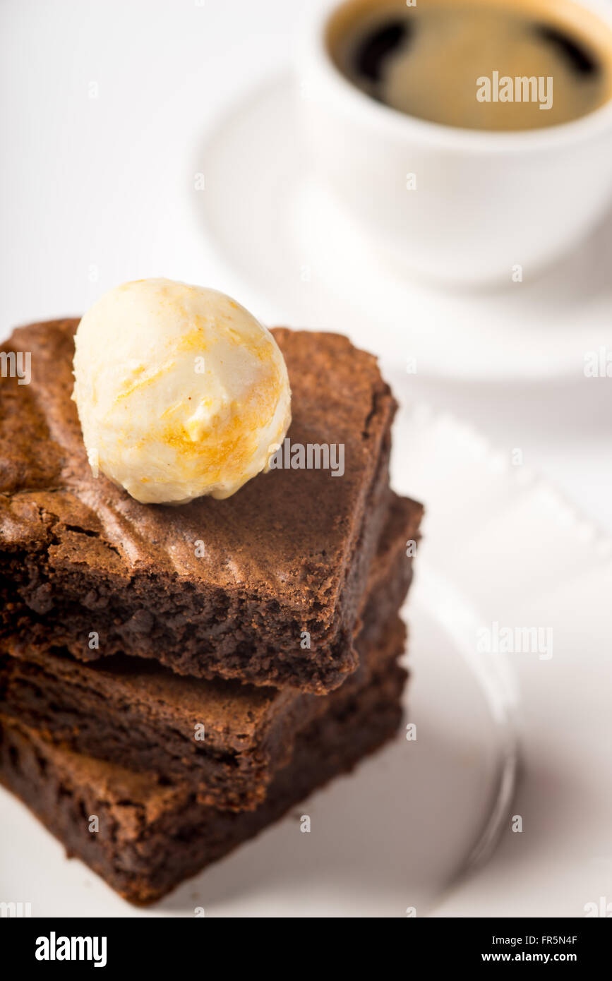 Brownie con gelato e una tazza di caffè sul tavolo in verticale Foto Stock