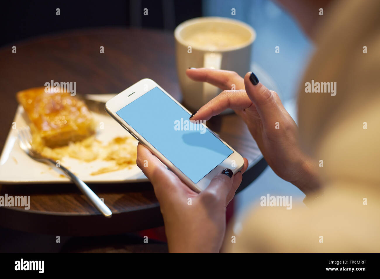 Ragazza con il suo smart phone a colazione in caffetteria Foto Stock