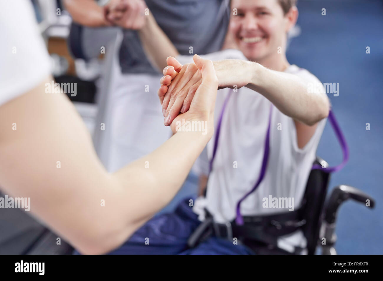 Fisioterapista tenendo le mani e uomo di sollevamento Foto Stock