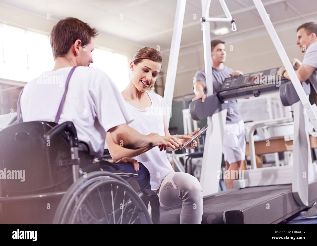 Fisioterapista che mostra digitale compressa a uomo in sedia a rotelle Foto Stock