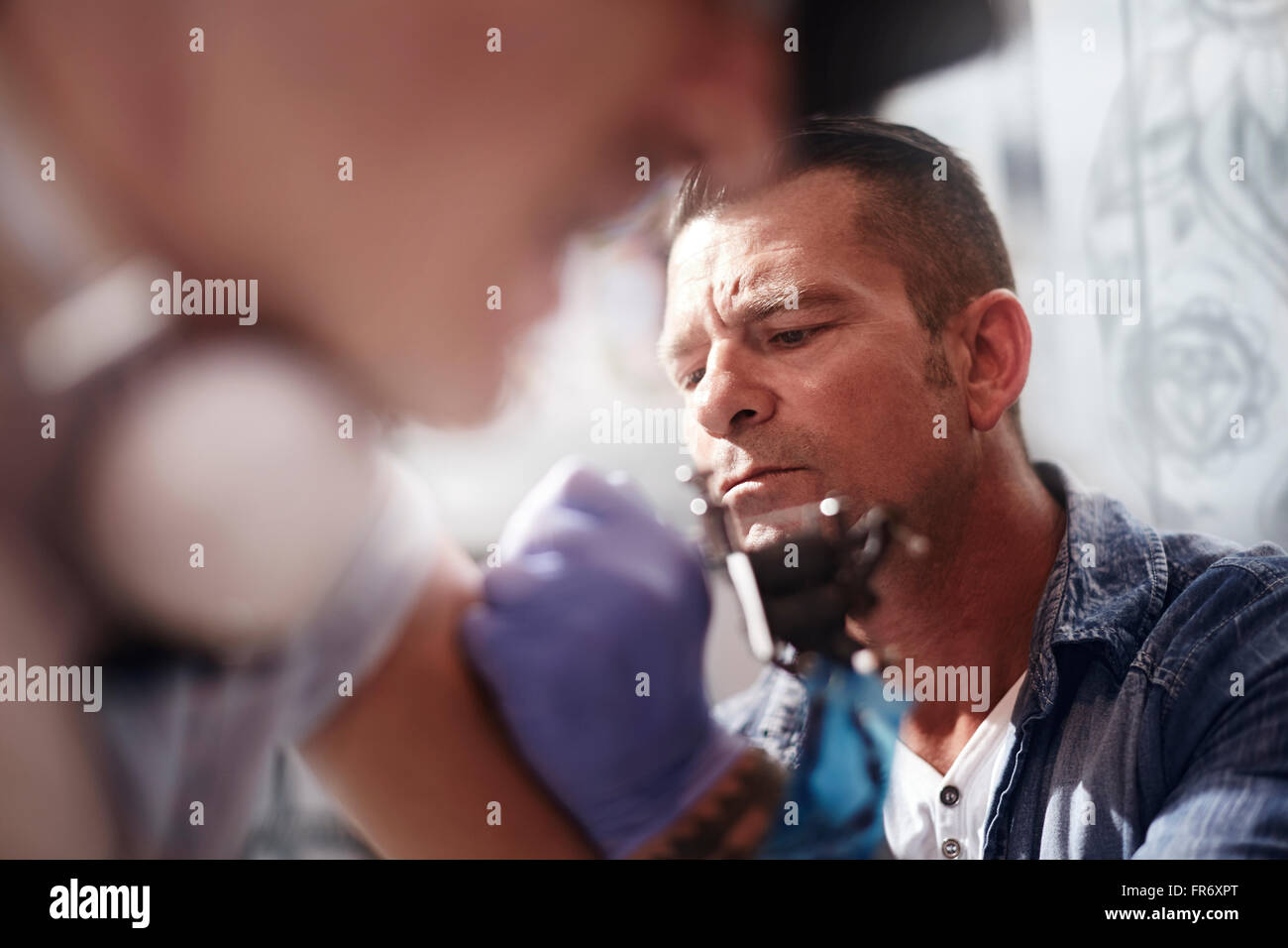 Focalizzato tattoo artist tatuaggio uomo del braccio Foto Stock