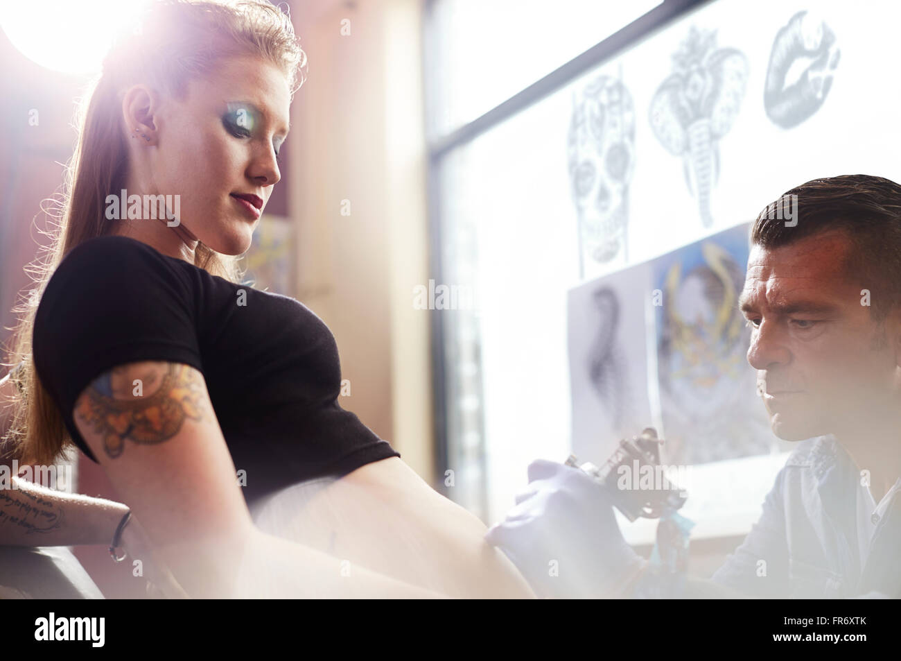Tattoo Artist tatuaggio donna di stomaco Foto Stock
