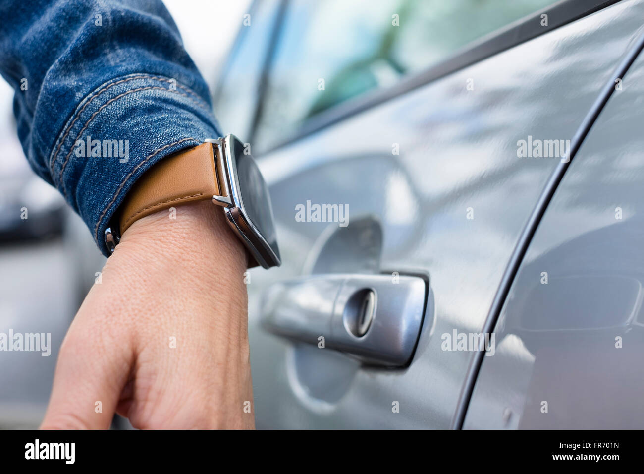 La donna apre la porta della sua vettura con un orologio da polso Foto Stock
