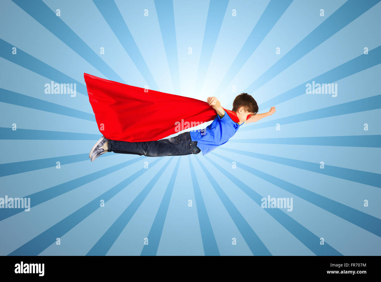 Ragazzo in rosso superhero cape e maschera e volare in aria Foto Stock