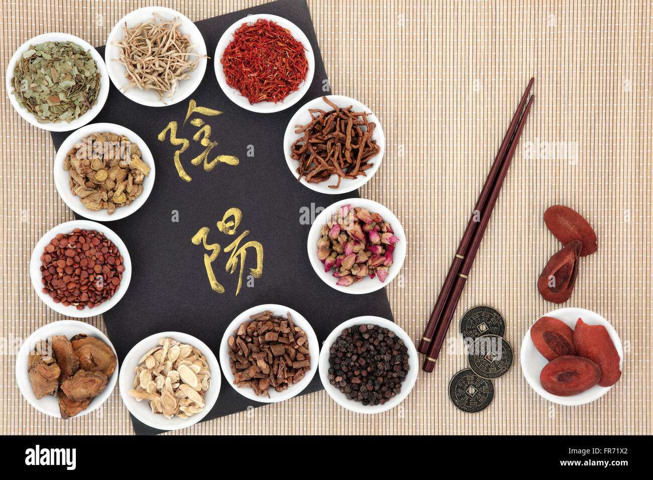 Yin e yang simboli, i Ching monete, bacchette e cinese tradizionale a base di erbe in porcellana bianca bocce oltre il bambù. Foto Stock