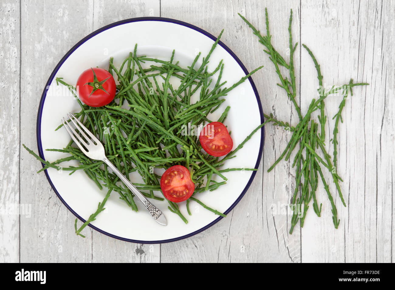 Samphire e vegetali di pomodoro super cibo su un piatto d'argento con forcella e lasco sul distressed bianco sullo sfondo di legno. Foto Stock