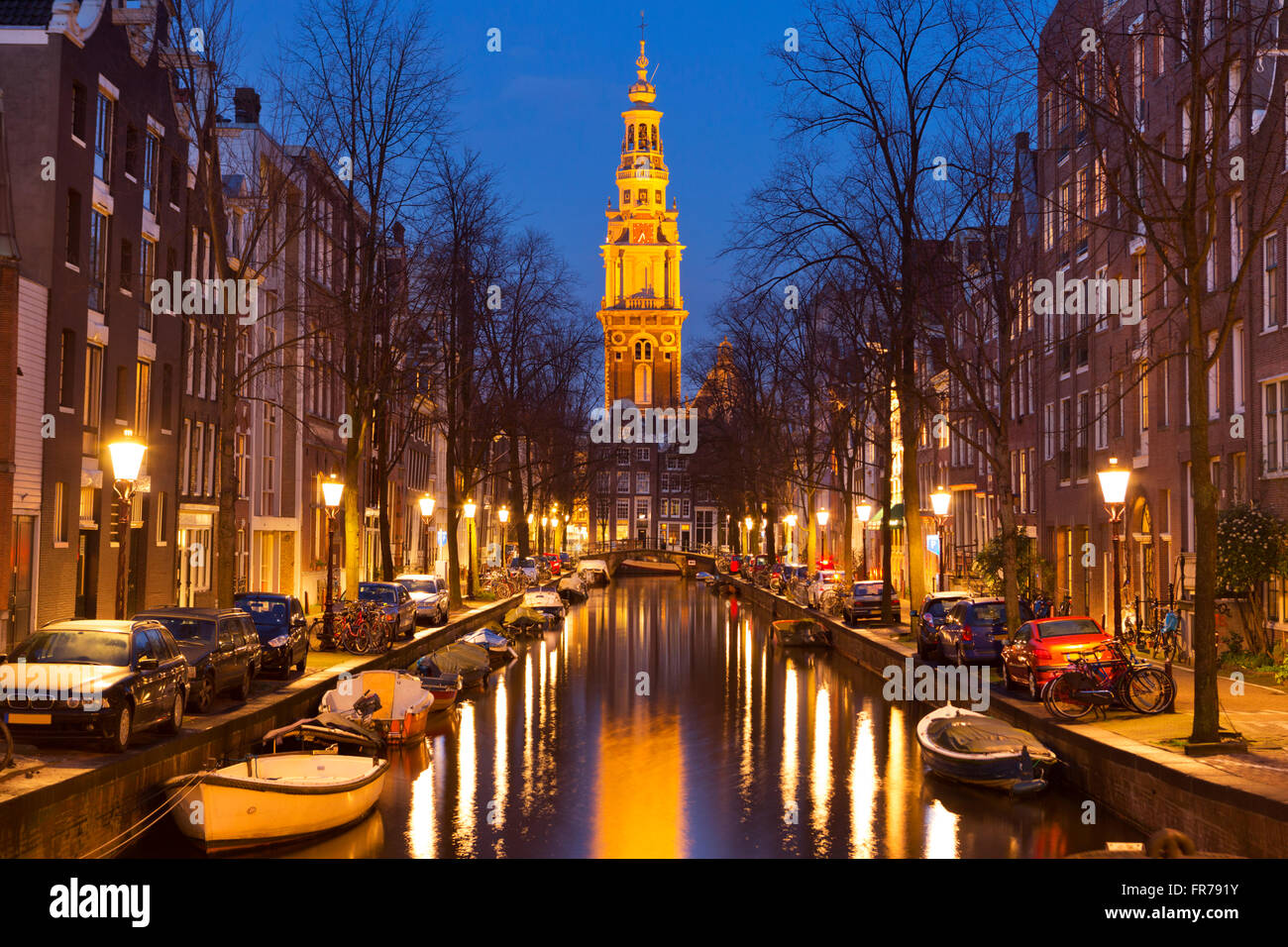 Torre di una chiesa alla fine di un canale nella città di Amsterdam, Paesi Bassi durante la notte. Foto Stock