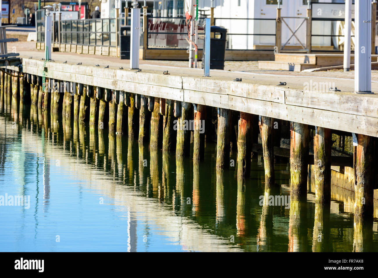 Alcune colonne di legno sotto un molo. L'acqua è il clam e ancora. Foto Stock