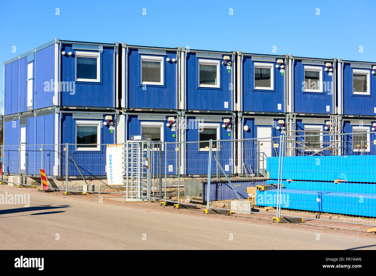 Kalmar, Svezia - 17 Marzo 2016: blu, impilabile lavoro modulare capannoni o uffici presso un sito in costruzione. Recinzione e strada in foregro Foto Stock