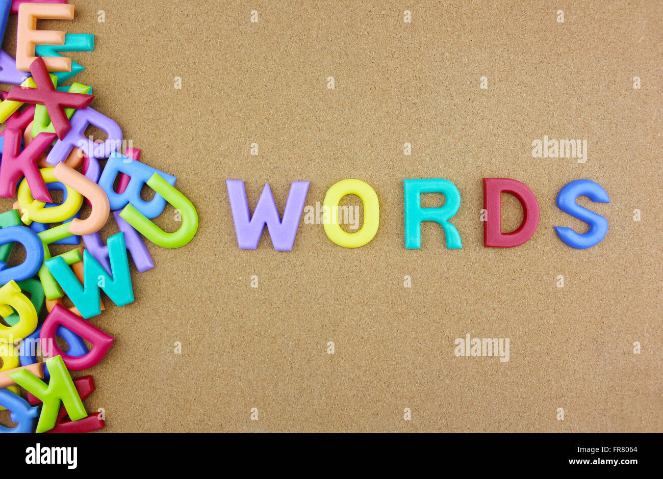 La colorita parola 'parole' accanto a una pila di altre lettere oltre il bordo marrone composizione superficiale. Foto Stock