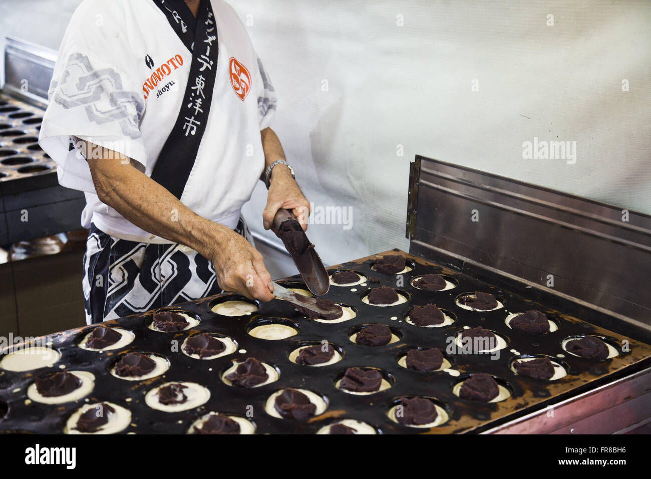 L'uomo la preparazione di dolci fagioli azuki chiamato imagawayaki Foto Stock