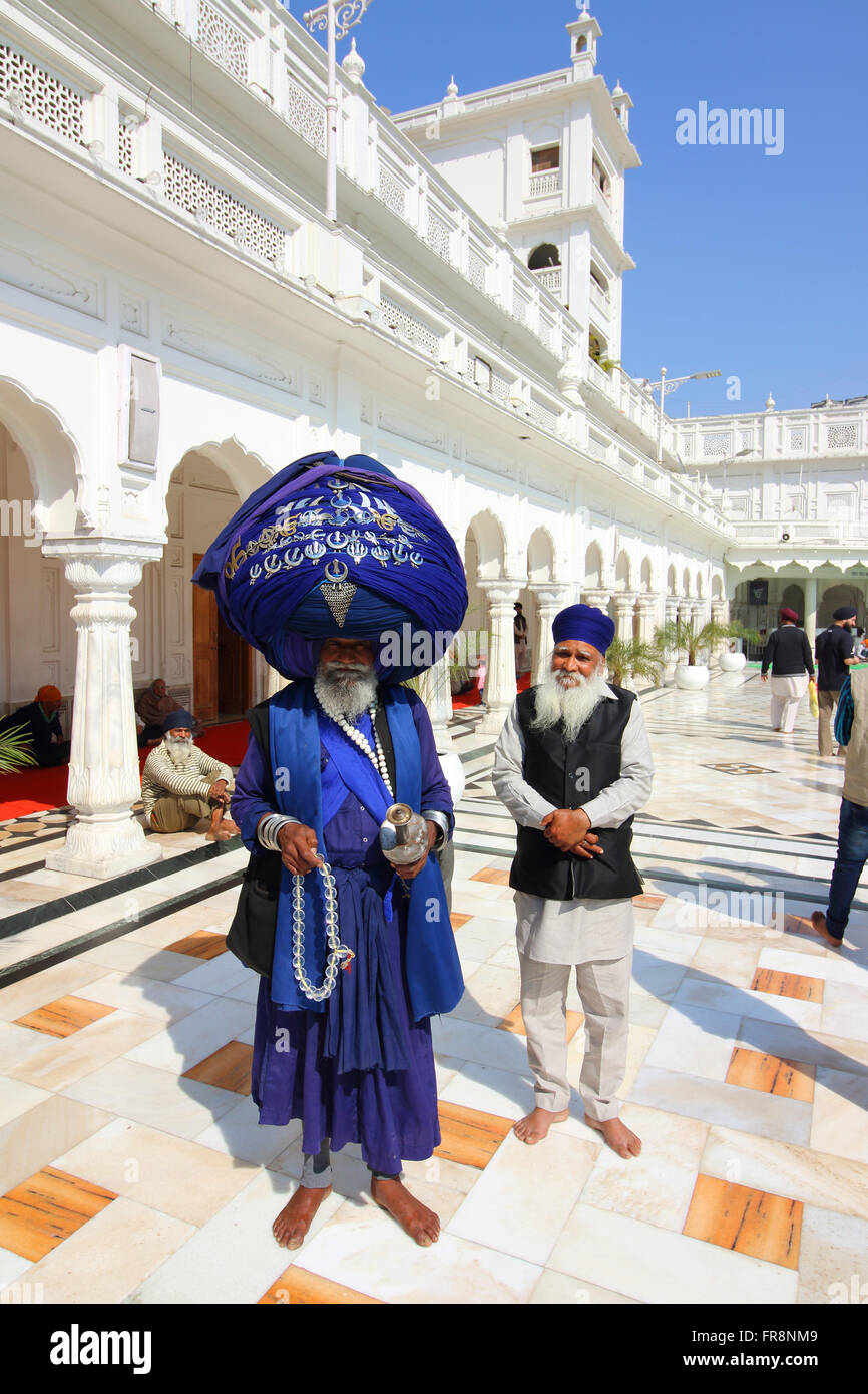 Un Nihang o Kalsa Sikh con pellegrini al tempio d'oro di Amritsar, centro della fede sikh. Foto Stock