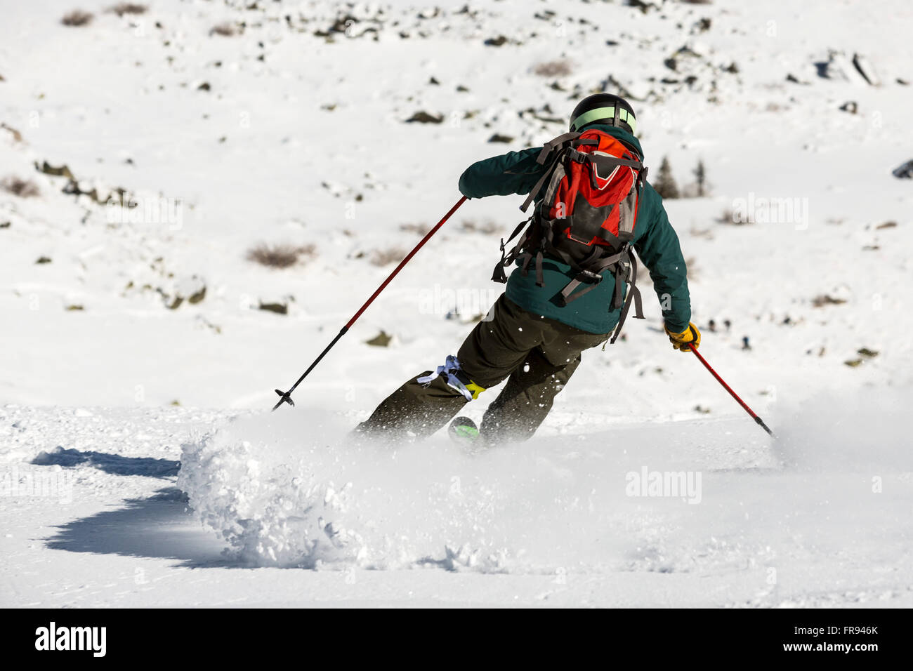 Un free rider è sciare giù un snowy Rocky Mountain top. Una foto dal suo retro. Velocità alta. Foto Stock
